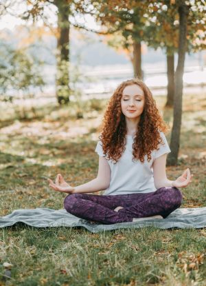 Woman meditating in a serene park during springtime, fostering relaxation and mental wellness.